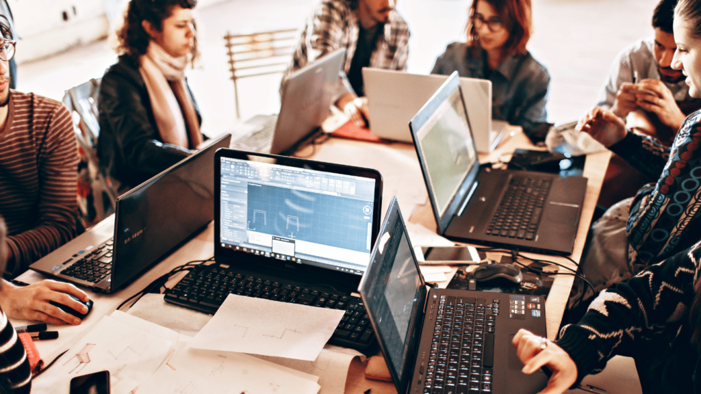 Team members on computers or laptops using different applications, with some screen sharing